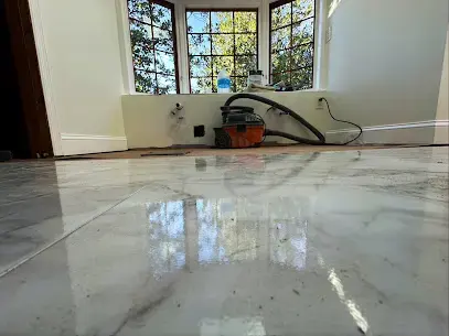Wet marble floor being vacuumed beside tall windows