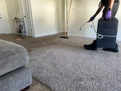 Technician extracting water from a wet carpet with a portable extraction unit